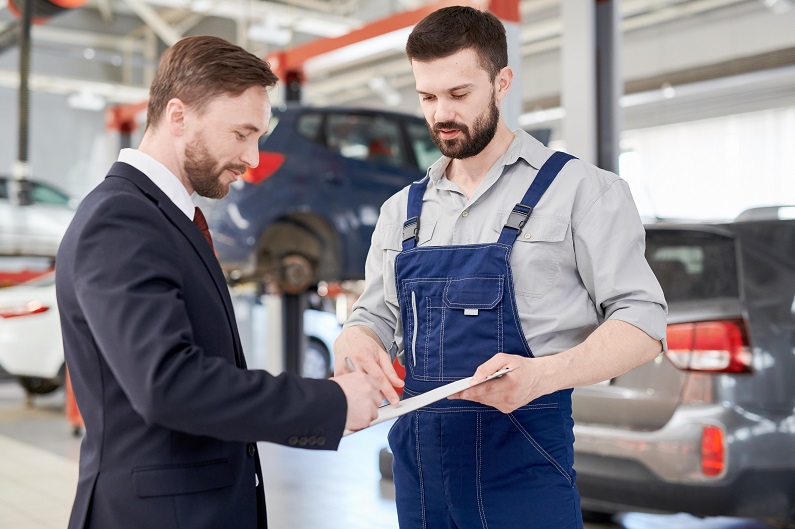 Businessman signing paperwork with mechanic